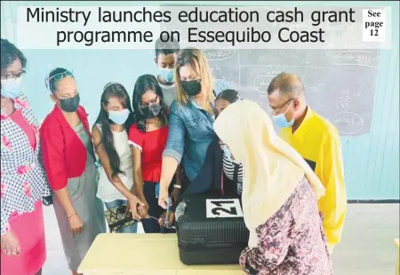  ?? (Ministry of Education photo) ?? Minister of Education Priya Manickchan­d cutting the seal off the first box containing the Because We Care Cash Grants at the Cotton Field Secondary School in the company of students, parents, teachers and regional officials.