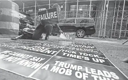  ?? USA TODAY NETWORK ?? Laura Arbeiter of New York City places anti- Donald Trump signs at Manhattan Criminal Courthouse.