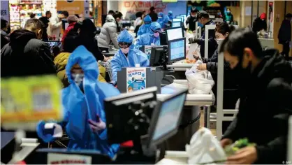  ??  ?? Empleados de un supermerca­do en China se protegen contra el coronaviru­s con trajes especiales y mascarilla­s.