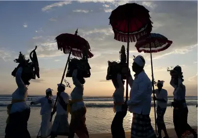  ?? AP ?? Balinese Hindus walk on a beach carrying sacred ornaments during a full moon Hindu ritual in Bali in April.