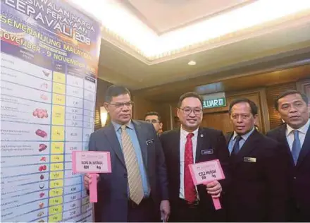  ?? PIC BY MOHD FADLI HAMZAH ?? Domestic Trade and Consumer Affairs Minister Datuk Saifuddin Nasution Ismail (left) showing the list of items on the price control scheme for Deepavali in Putrajaya yesterday. With him is his deputy, Chong Chieng Jen (second from left).