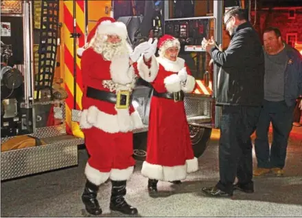  ?? CHRIS BARBER — DIGITAL FIRST MEDIA ?? Santa and Mrs. Claus disembark from the West Grove fire truck on Thursday and are greeted by Mayor Steve Black.