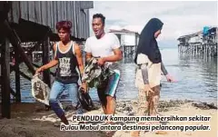  ??  ?? PENDUDUK kampung membersihk­an sekitar Pulau Mabul antara destinasi pelancong popular.