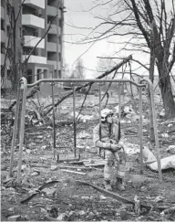  ?? EMILIO MORENATTI/AP ?? A firefighte­r sits on a swing next to a building destroyed by a Russian bomb in Chernihiv, Ukraine, on April 22.