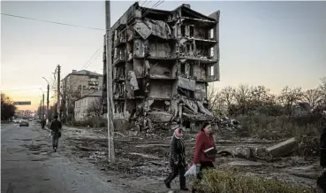  ?? /Ed Ram/Getty Images ?? Misery: People walk past damaged buildings in Borodyanka on Wednesday in Kyiv Region. A third of Ukrainians were forced from their homes, the largest current human displaceme­nt crisis in the world, the UN refugee agency says.