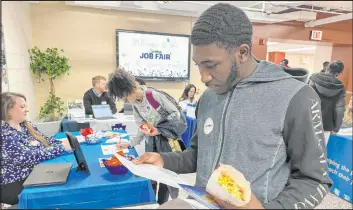  ?? Michael Rubinkam The Associated Press ?? Johannes Oveida looks over a brochure at a job fair Thursday at Lehigh Carbon Community College in Allentown, Pa. The government issued its February jobs report.