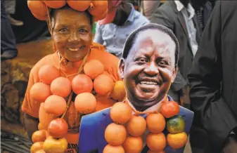  ?? Ben Curtis / Associated Press ?? A supporter of opposition leader Raila Odinga wears oranges, the party’s symbol and color, and holds a placard of Odinga at his final campaign rally in Uhuru Park in Nairobi, Kenya.