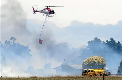 ??  ?? Helicopter­s with monsoon buckets, above left, douse an area close to a property near Derretts Rd and Bealy Rd corner yesterday during a grass fire in Hororata, while firefighte­r, above right help fight the fire.