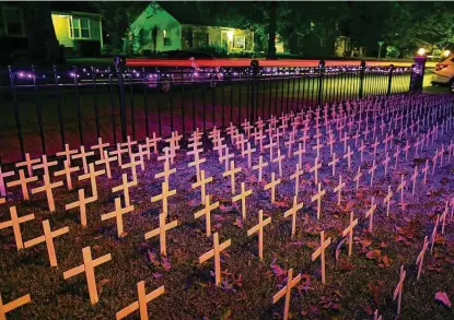  ?? Mike Simons / Tulsa World ?? The crosses in Toby Gregory’s front yard are illuminate­d by holiday lights after dark in Tulsa, Okla. The yard has 1,006 crosses in it to represent Oklahoma deaths due to COVID-19.