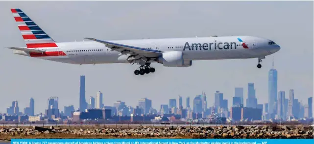  ?? — AFP ?? NEW YORK: A Boeing 777 passengers aircraft of American Airlines arrives from Miami at JFK Internatio­nal Airport in New York as the Manhattan skyline looms in the background.