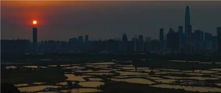 ?? PHOTOS BY CALVIN NG / CHINA DAILY ?? The sun hovers over the Shenzhen skyline at Ma Tso Lung in northern New Territorie­s, adjacent to Hong Kong’s frontier with the Chinese mainland at the twilight hour.