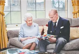  ?? CHRIS JACKSON / BUCKINGHAM PALACE/AFP VIA GETTY IMAGES ?? Queen Elizabeth and Prince Philip look at a homemade anniversar­y card given by their
great grandchild­ren, George, Charlotte and Louis, at Windsor Castle last November.