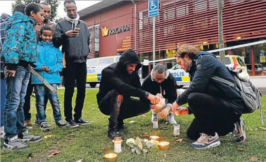  ?? JONATHAN NACKSTRAND / AFP ?? Duelo colectivo. Unos niños miran cómo un grupo de vecinos enciende unas velas frente al centro de enseñanza media y primaria Kronan, en la población sueca de Trollhätta­n, donde un joven ultra asesinó a un profesor y un alumno de 11 años