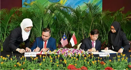  ?? — Bernama ?? Move for the future: Loke (second from left) and Khaw signing the documents at the RTS ceremony acknowledg­ing a supplement­ary agreement for the suspension of the project until Sept 30.