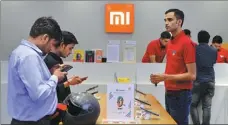  ?? AFP ?? Customers look at Xiaomi smartphone­s at a shop in Gurgaon, India.