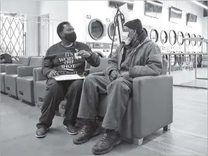  ?? TERESA CRAWFORD/ASSOCIATED PRESS ?? Herman Simmons, left, chats with Theopulis Polk at a Chicago laundromat early this month and helps the 62-year-old make a vaccinatio­n appointmen­t.