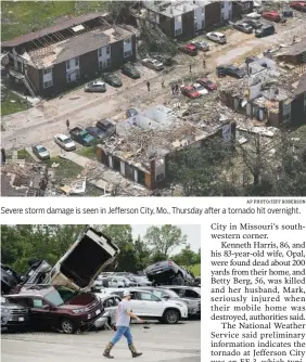  ?? AP PHOTO/CHARLIE RIEDEL AP PHOTO/JEFF ROBERSON ?? Severe storm damage is seen in Jefferson City, Mo., Thursday after a tornado hit overnight. A worker walks past tornado-damaged vehicles at a dealership in Jefferson City, Mo., on Thursday after a tornado tore though late Wednesday.