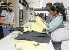  ?? LEON LESTRADE African News Agency (ANA) ?? GEM Schoolwear manager, Muhammed Patel, assists Nivashini Pillay with her selection of uniforms. |