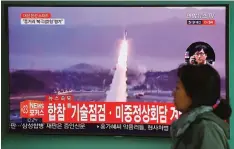  ?? —AFP ?? SEOUL: A woman walks past a television screen showing file footage of a North Korean missile launch, at a railway station in Seoul yesterday.