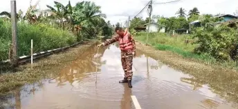  ?? ?? A Bomba Marudi personnel measures the floodwater level at a village.