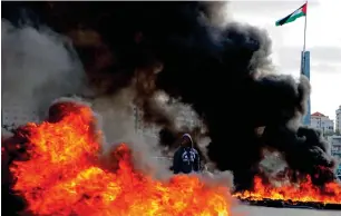  ?? AFP ?? BURNiNG RaGE: a Palestinia­n stands between burning tyres during clashes with israeli troops during a protest at the Jewish settlement of Beit El, near the West Bank city of Ramallah, on Thursday. —