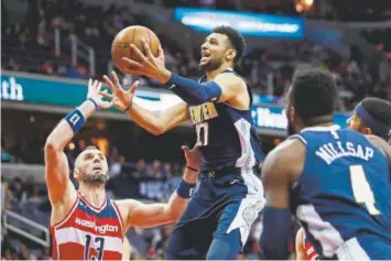  ??  ?? Nuggets guard Jamal Murray drives to the basket Friday night against the Wizards’ Marcin Gortat in Washington. Murray made 8-of-20 shots, including 5-of-12 attempts from 3-point range, and contribute­d 25 points and six rebounds to Denver’s 108-100...