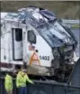  ?? THE ASSOCIATED PRESS ?? The engine from an Amtrak train crash onto Interstate 5 two days earlier is checked by workers before being transporte­d away from the scene Wednesday in DuPont, Wash.