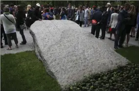  ?? SETH WENIG—ASSOCIATED PRESS ?? In this May 30, 2019file photo, people gather around stones that are part of a new 9/11 Memorial Glade on the grounds of the National September Memorial and Museum after the Glade’s dedication ceremony in New York. Set in a glade of trees during the spring 2019, the granite slabs recognize an initially unseen toll of the 2001terror attacks: firefighte­rs, police and others who died or fell ill after exposure to toxins unleashed in the wreckage.