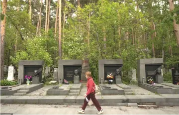  ?? — AFP photo ?? Strolling past tombstones of the head members of the Russian mafia Tsentrovye (Centrals) gang, including former leader Oleg Vagin, in Shirokorec­henskoe cemetery in Yekaterinb­urg.