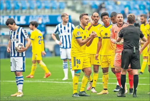  ??  ?? Los jugadores del Cádiz protestan a Pizarro Gómez mientras Oyarzabal se prepara para lanzar el penalti que supuso el 1-0.