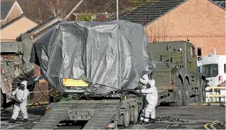  ?? PHOTOS: AP ?? Investigat­ors in gas masks move a wrapped ambulance from the South Western Ambulance Service station in Harnham, near Salisbury, England, as police and members of the armed forces probe the suspected nerve agent attack on Russian spy double agent...