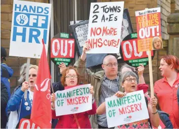  ?? — AFP ?? Protesters with anti-Conservati­ve and anti-cuts banners and placards demonstrat­e outside the venue where Prime Minister Theresa May and government ministers launched the Conservati­ve Party general election manifesto in Halifax in northern England on...