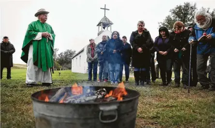  ?? Bob Owen / Staff photograph­er ?? Father Roy Snipes gathers with parishione­rs around a fire following an early morning Mass at La Lomita Chapel, a historical site south of the levee in Mission that could fall victim to President Donald Trump’s border wall.