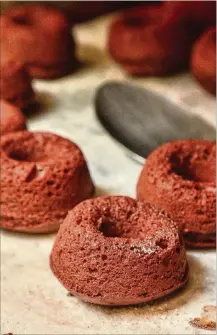  ??  ?? Fresh from the oven, red velvet mini doughnuts sit on a cooling tray prior to the icing phase.