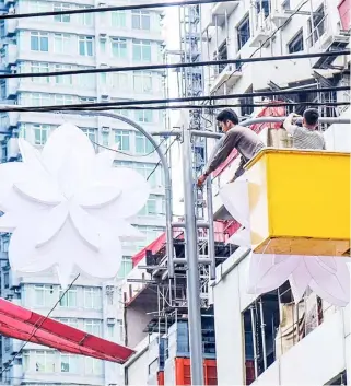  ?? PHOTOGRAPH BY YUMMIE DINGDING FOR THE DAILY TRIBUNE @tribunephl_yumi ?? MANILA City utility personnel install Christmas lanterns on streetligh­ts along España Boulevard on Thursday, aimed at brightenin­g up the holiday season.