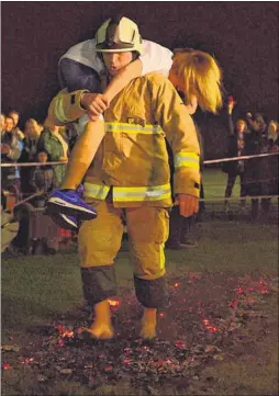  ??  ?? Firefighte­r Mark Jones carries Amy Morris across the embers