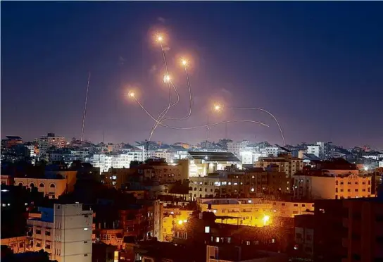  ?? MOHAMMED ABED/AFP VIA GETTY IMAGES ?? Above, Israel’s Iron Dome air defense system intercepte­d rockets launched from Gaza City on Wednesday as Palestinia­ns