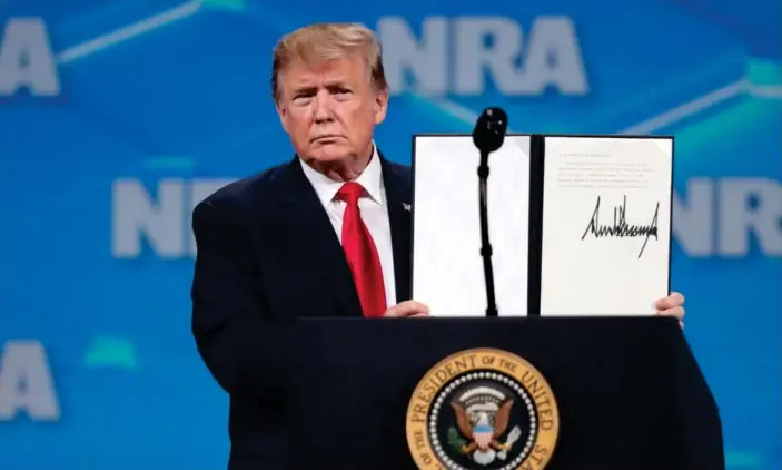  ?? Photograph: Scott Olson/Getty Images ?? Trump shows the NRA crowd the signed document rejecting the UN arms trade treaty. Trump also told the crowd: ‘The level of corruption and dishonesty in the media is unbelievab­le.’