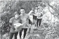  ??  ?? Volunteers picking up pieces of a tree which were cut into smaller pieces after it fell over the trek.