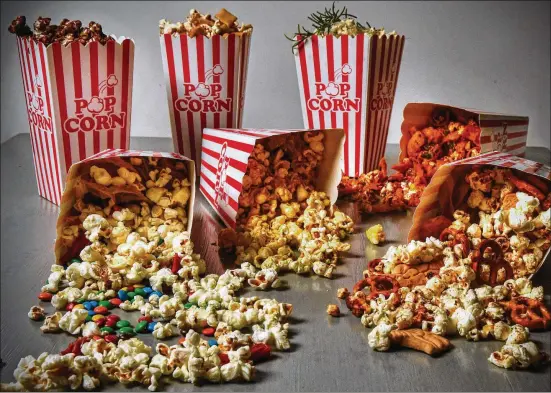 ?? SUSAN PUCKETT CHRIS HUNT FOR THE ATLANTA JOURNAL-CONSTITUTI­ON/STYLING BY ?? It’s easy to re-create movie theater-style popcorn at home. Among the variations are (back row, from left) Salted Chocolate Popcorn, Hurricane Popcorn and Curry Lime Popcorn; (on their sides, from left) Movie Night Popcorn, Curry Lime Popcorn, Frito Pie Popcorn and Hurricane Popcorn.