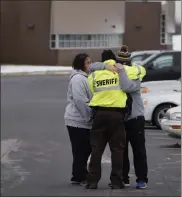  ?? Paul sancya / ap ?? an oakland county sheriff’s deputy hugs family members of a student in the parking lot of oxford high school in oxford, mich., wednesday.