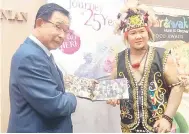  ?? ?? BUKU: Pemain sape terkemuka Sarawak Desmond Junek menyerahka­n buku ‘The Rainforest World Music Festival - A Journey of 25 Years’ semasa majlis pelancaran­nya semalam.