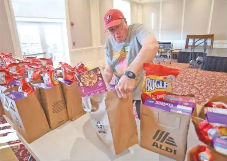  ?? STAFF PHOTO BY MATT HAMILTON ?? Volunteer Hugh Moore organizes bags Wednesday as the Brainerd Community Food Pantry distribute­s food at Brainerd United Methodist Church.