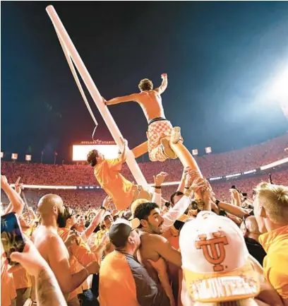  ?? WADE PAYNE/AP ?? Tennessee fans tear down the goal post after defeating Alabama 52-49 on Saturday in Knoxville, Tenn.