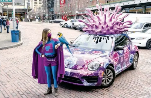  ?? Agence France-presse ?? ↑
Lin Wilson, a volunteer against COVID-19, stands near her Quidel Flu Bug topped with a giant replica of the virus in Seattle, Washington, on Thursday.