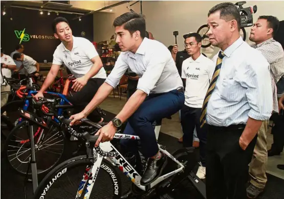  ??  ?? Testing it out: Youth and Sports Minister Syed Saddiq Syed Abdul Rahman (second from left) giving the e-cycling bike a try with former national cyclist Josiah Ng (left) yesterday. Looking on is National Sports Council director-general Datuk Ahmad Shapawi Ismail (right). — SAM THAM/ The Star
