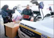  ?? PETER HVIZDAK - NEW HAVEN REGISTER ?? Metashar Dillon, Chairman and CEO of Kingdom Internatio­nal Economic Developmen­t Corp., left, and New Haven Police Officer Hector Valentin organize donations at the WalMart in New Haven during a stuff-a-cruiser to benefit the KIEDC and Mae Ola Riddick...