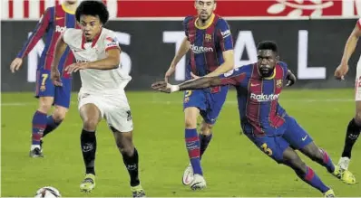  ?? Julio Muñoz / Efe ?? Koundé se escapa de Umtiti y Busquets en la jugada en que marcó el 1-0 del Sevilla en el Sánchez Pijzuán.