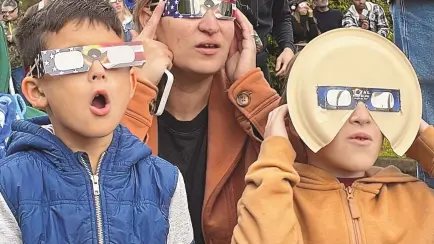  ?? CLAIRE RUSH/ASSOCIATED PRESS ?? Samia Harboe, her son Logan and her friend’s son wear eclipse glasses during totality of the annular solar eclipse in Eugene, Ore., on Oct. 14, 2023. Her family came with glasses they’d made for the 2017 total eclipse and said they were excited to see another one.
