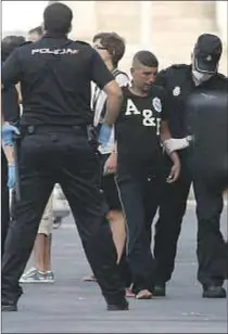  ?? EFE/Carlos Barba ?? Un policía, junto a un grupo de inmigrante­s, en el patio del CIE de Barcelona. A la derecha, unos policías con un migrante en el puerto de Almería